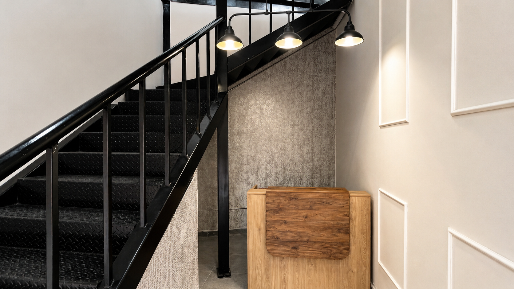 Recepción con escalera negra y lámparas industriales — Entrada al estudio L'ATELIER 64